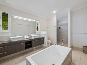 Un baño con dos lavabos y un espejo grande. en Banksia Beach House by Discover Stradbroke, en Point Lookout