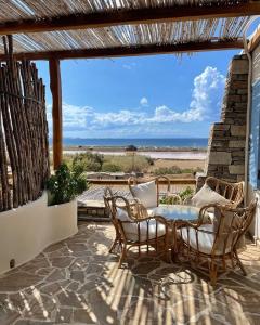 een patio met stoelen en een tafel en uitzicht op het strand bij KYMA Apartments - Naxos Agios Prokopios in Agios Prokopios