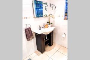 un baño con lavabo y espejo en Summerstrand Boutique Beach Apartment, en Summerstrand 37 fotos más