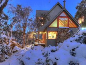 a house covered in snow at night at Indi Chalet in Thredbo