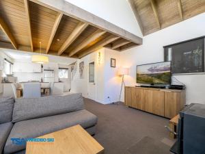 a living room with a couch and a flat screen tv at Indi Chalet in Thredbo