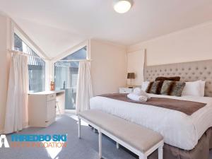 a white bedroom with a large bed and a window at Kaella in Thredbo