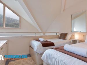 a attic bedroom with two beds and a window at Kaella in Thredbo
