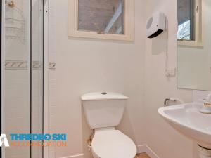 a white bathroom with a toilet and a sink at Kaella in Thredbo