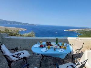 a blue table with food and drinks on a balcony with the ocean at Ustrine view in Ustrine