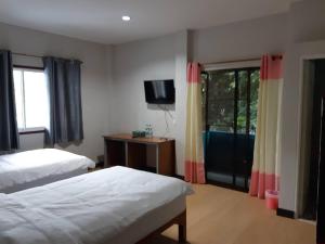 1 dormitorio con 2 camas, TV y ventana en แสงสินธ์เฮ้าส์ Shangsin House, en Mae Hong Son