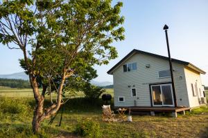 a small house in a field next to a tree at agris FURANO 01 FARM GUEST HOUSE in Nunoppe