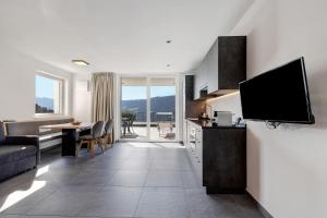 uma cozinha e sala de estar com televisão e sofá em Thalerhof Naturae Rupes em Auna di Sotto