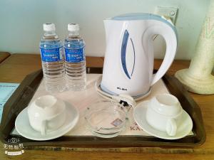 a tray with a tea kettle and cups and water bottles at Kawan Hotel in Sibu