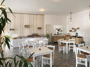a restaurant with white tables and chairs and a kitchen at Asteri Hotel in Livadi