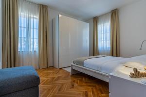 a bedroom with a bed and a couch and windows at House Catania in Mali Lošinj