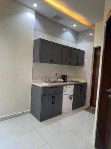 a kitchen with gray cabinets and a white counter top at منازل بلقيس للشقق المخدومة in Hail