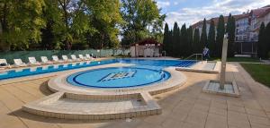 a swimming pool with chairs and a person standing next to it at Panoráma Lux Wellness apartman in Hajdúszoboszló