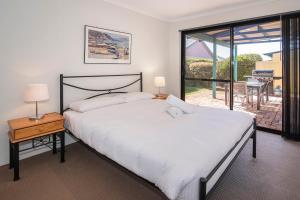 a bedroom with a large bed and a balcony at Dunsborough Beach Cottages in Dunsborough