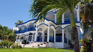 a blue and white house with a palm tree at casaenjoysamana in Los Naranjos