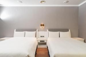 2 camas en una habitación de hotel con sábanas blancas en Yilan Fu Hsiang Hotel, en Yilan City