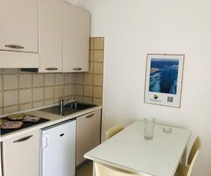 a small kitchen with a white table and a sink at NRH Stintino Beach Garden in Stintino