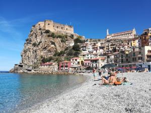 a group of people sitting on a beach with a castle at Casa Vacanze Scilla in Scilla