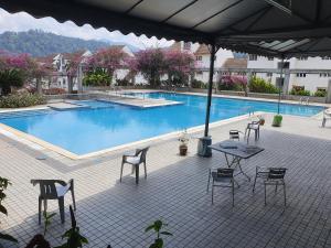 a patio with a table and chairs next to a pool at Selesa Hillhomes Golf Resort - T11L1Ga in Bentong +9 photos