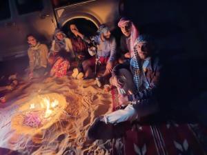a group of people sitting around a fire at Bubble RumCamp in Wadi Rum