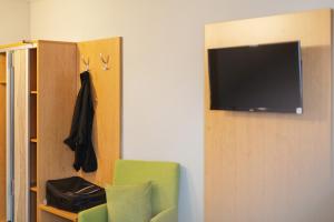 a living room with a tv and a green chair at Novum Hotel Bruy in Stuttgart