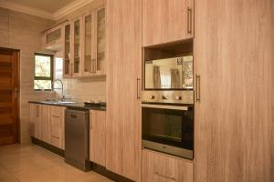 uma cozinha com armários de madeira, um forno e um lavatório em Apartment Two-One-Two Eleven em Gaborone