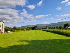 un gran campo de césped verde con montañas en el fondo en Shadowvale E34X773 en Tipperary
