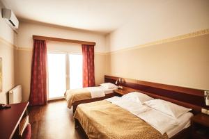 a hotel room with two beds and a window at Hotel Vila Emei in Maribor