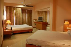 um quarto de hotel com duas camas e uma televisão em Savoy Greens Karnal em Karnal