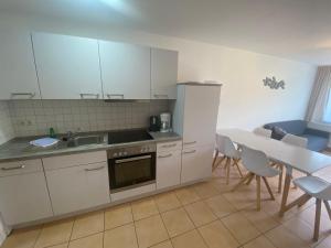a kitchen with white cabinets and a table with chairs at FeWo im Camp Am Wasser in Juliusruh