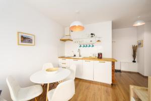 una cucina bianca con un tavolo e sedie bianche di APT Nadmorskie - Solne a Kołobrzeg
