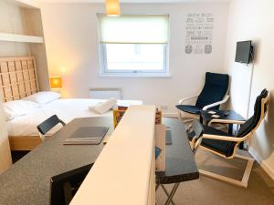 Cette chambre comprend un lit, une table et des chaises. dans l'établissement Glasgow City Centre Studio Apartment, à Glasgow