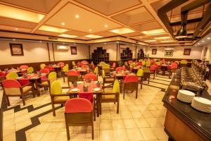 Hotel Nirvana by Luxury International في بهيراهاوا: مطعم به طاولات وكراسي حمراء وصفراء