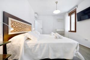 a white bedroom with a large white bed in it at Tejón y Marín, nuevo apartamento en casco antigüo in Córdoba