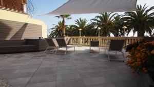a patio area with chairs, tables and umbrellas at Piccolo Hotel in Moneglia