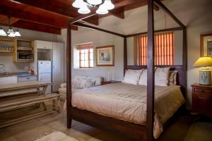 a bedroom with a canopy bed and a kitchen at Milkwood at Kransfontein Estate in Stilbaai
