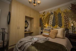 a bedroom with a bed with a painting on the wall at AUGE 44 GUEST APARTMENTS in Swellendam