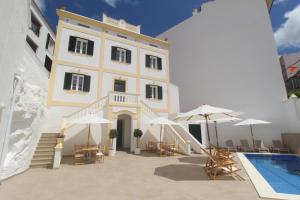 - un bâtiment avec une piscine, des chaises et des parasols dans l'établissement Hotel Amano Maison Carrée, à Alaior