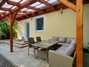 een patio met een bank en een tafel met stoelen bij Fövenyes House in Balatonudvari