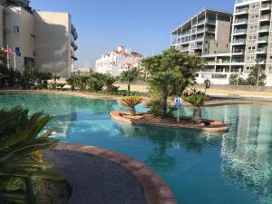 a large pool of water with palm trees and buildings at Family apartment with swimming pools 3 bedroom 2 bathroom Rock facing in Gibraltar