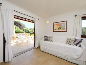 a white room with a bed and a sliding glass door at Holiday Home Canayli by Interhome in Aglientu