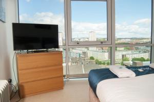 a bedroom with a television on a dresser in front of a window at City Views Apartment City Centre FreeParking in Glasgow