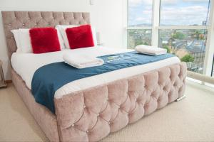 a large bed with red pillows and a large window at City Views Apartment City Centre FreeParking in Glasgow
