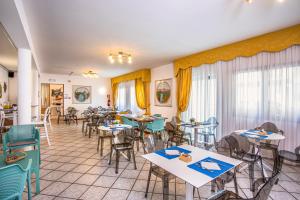 un restaurant avec des tables, des chaises et des fenêtres dans l'établissement Hotel Diana, à Lido di Jesolo