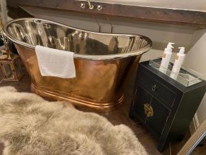 a large copper tub sitting in a bathroom with a rug at The Hive at Poppi-Red in Hawkshead