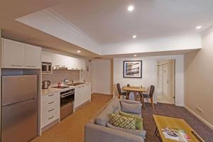 a kitchen and living room with a couch and a table at Quality Apartments Adelaide Central in Adelaide