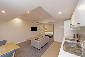 a kitchen and living room with a couch and a bed at Quality Apartments Adelaide Central in Adelaide