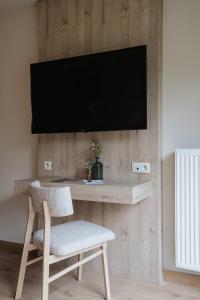 a television on a wall with a chair and a desk at La Merveilleuse by Infiniti hôtel in Dinant