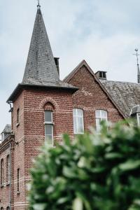 a tall brick building with a clock on it's side at La Merveilleuse by Infiniti Resorts in Dinant