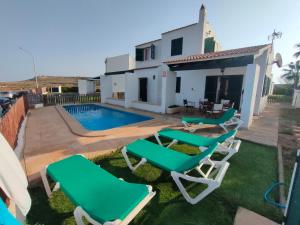 a villa with a swimming pool and two lawn chairs at Villa Victor - Primera linea mar, vista a puesta de sol in Cala en Blanes